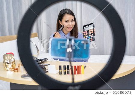 Glamour Asian woman beauty blogger or vlogger showing make up with palette and Live on social network media via video or mobile phone, video recording by herself,makeup tutorial,cosmetics vlog concept 61686072