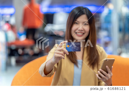 Portrait Asian woman holding and presenting the credit card for online shopping in department store over the clothes shop store background, technology money wallet and online payment concept Portrait Asian woman holding and presenting the credit card for online shopping in department store over the clothes shop store background, technology money wallet and online payment concept 61686121