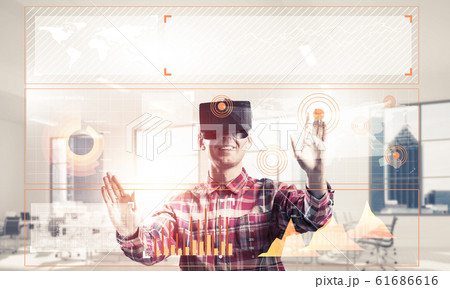 Young man in modern office interior experiencing virtual reality 61686616