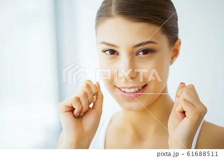 Health and Beauty. Beautiful Young Girl With White Teeth Cleans Teeth With Dental Floss. A Woman With A Beautiful Smile. Tooth Health Health and Beauty. Beautiful Young Girl With White Teeth Cleans Teeth With Dental Floss. A Woman With A Beautiful Smile. Tooth Health 61688511