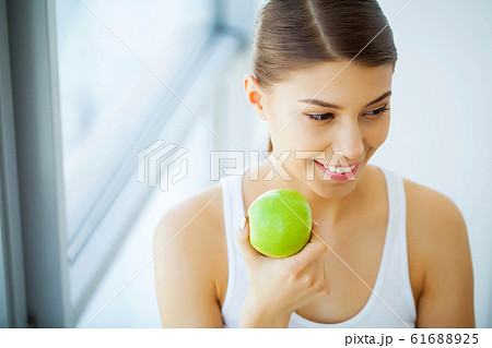 Health and Beauty. Beautiful Young Girl With White Teeth Holding Hands Of Fresh Green Apple. A Woman With A Beautiful Smile. Tooth Health 61688925