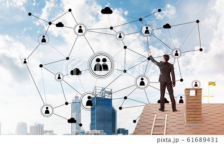 Businessman on house roof presenting networking and connection concept. Mixed media Businessman on house roof presenting networking and connection concept. Mixed media 61689431
