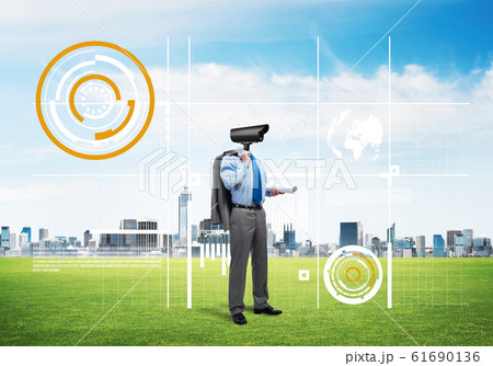 Camera headed man standing on green grass against modern cityscape Camera headed man standing on green grass against modern cityscape 61690136