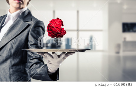 Hand of waiter presenting crampled paper lightbulb 61690392