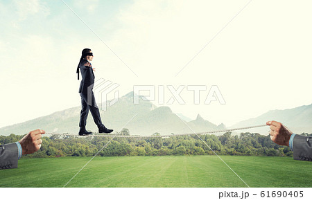 Business concept of risk support and assistance with man balancing on rope 61690405