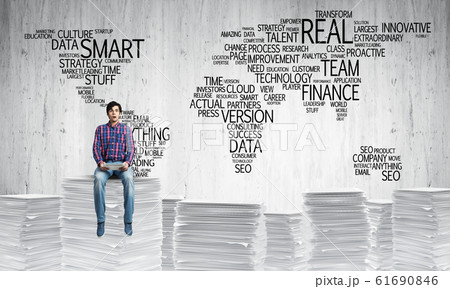 Attractive man sitting on pile of paper documents. Attractive man sitting on pile of paper documents. 61690846
