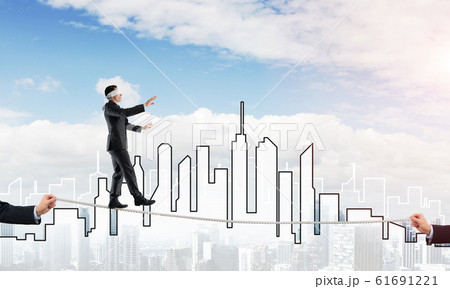 Business concept of risk support and assistance with man balancing on rope Business concept of risk support and assistance with man balancing on rope 61691221