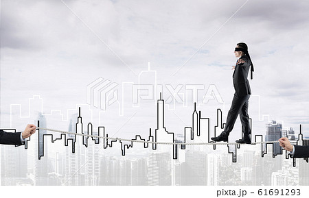 Business concept of risk support and assistance with man balancing on rope Business concept of risk support and assistance with man balancing on rope 61691293