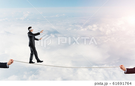 Business concept of risk support and assistance with man balancing on rope Business concept of risk support and assistance with man balancing on rope 61691764