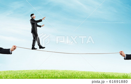 Business concept of risk support and assistance with man balancing on rope Business concept of risk support and assistance with man balancing on rope 61691880