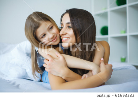 Woman and young girl lying in bed smiling 61693232