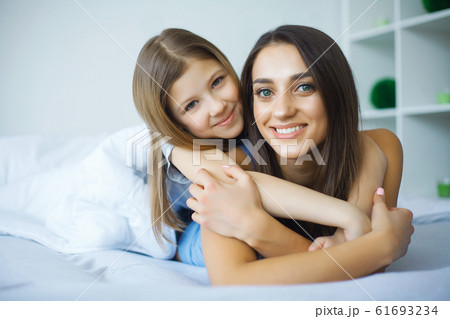 Woman and young girl lying in bed smiling 61693234