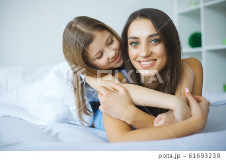 Woman and young girl lying in bed smiling 61693239