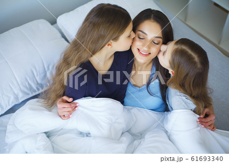 Woman and young girl lying in bed smiling Woman and young girl lying in bed smiling 61693340