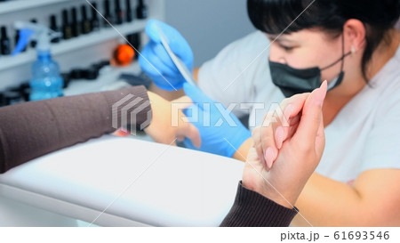 Manicurist files a nail with a nail file to a client. Manicure process, nail extension. close-up 61693546