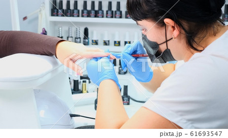 Manicurist paints the nails of a beautiful hand in a beauty salon. Gel polish. Lacquer. Manicure 61693547
