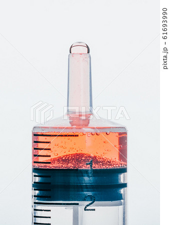 Medical Syringe with needle isolated on white, macro. Isolated syringe filled with red medication liquid. Fluid is like blood with bubbles. 61693990