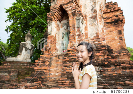 Cute happy smiling tourist girl,Asian cute girl with pay respect on statue of buddha background at Wat Mahathat is a Buddhist temple in the city of Ayutthaya Historical Park,Thailand,travel concept. 61700283