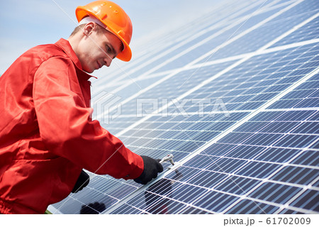 Technician is installing solar cell to save energy against the blue sky Technician is installing solar cell to save energy against the blue sky 61702009