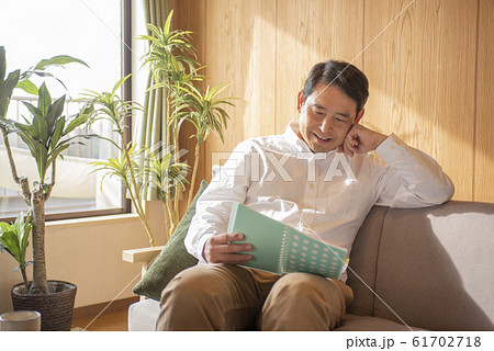 リビングでのんびり本を読む中高年の男性 リビングでのんびり本を読む中高年の男性 61702718
