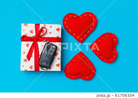 Top view of car key on gift box and red textile 61706304