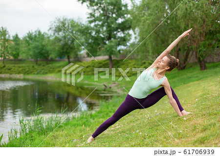 A young sports girl practices yoga on a green lawn 61706939