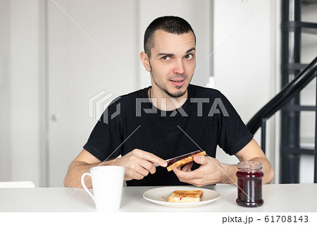 The guy has breakfast with toast with jam. The guy has breakfast with toast with jam. 61708143