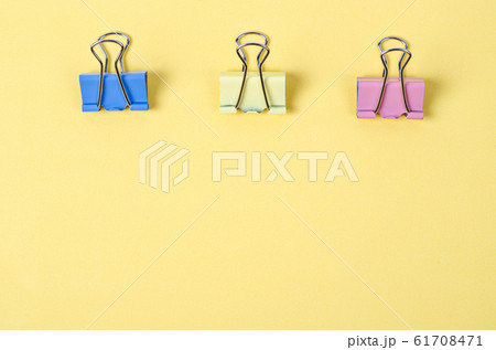 Colorful binder clips on yellow paper background. 61708471