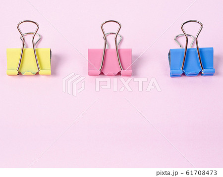 Colorful binder clips on pink paper. 61708473