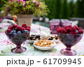Beautiful glasses of colored purple glass on the table with berries and flowers 61709945
