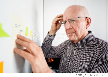 Elderly man with dementia looking at notes Elderly man with dementia looking at notes 61709972