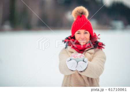Female hands holdink white cup of coffee with white and pink marshmallows Female hands holdink white cup of coffee with white and pink marshmallows 61710061