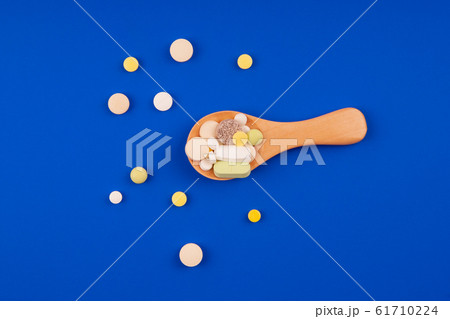 Medical pills with a wooden spoon on a blue background Medical pills with a wooden spoon on a blue background 61710224