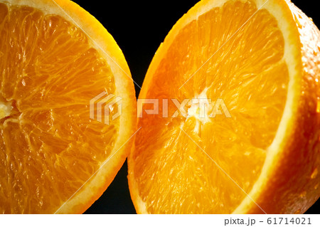 Fresh halves of orange with water droplets on black background Fresh halves of orange with water droplets on black background 61714021