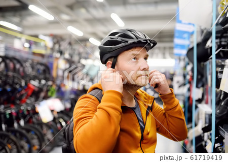 Middle age man choosing and try bicycle helmet Middle age man choosing and try bicycle helmet 61719419