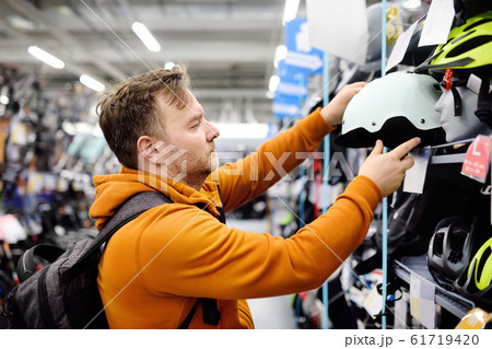 Middle age man choosing bicycle helmet in sport shop Middle age man choosing bicycle helmet in sport shop 61719420