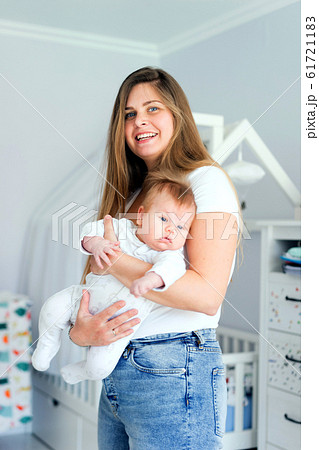Pretty blond mom and newborn son in her arms in the white children room Pretty blond mom and newborn son in her arms in the white children room 61721183