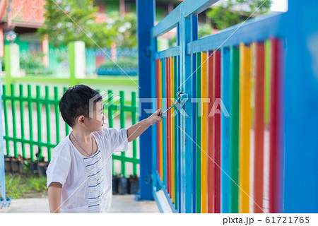 Sad Asian kid behind the grid trying to escape. Sad Asian kid behind the grid trying to escape. 61721765