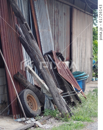 stack of old grunge galvanized metal sheet and rustic iron pipes old hardwood and a defect wheel on outside wall of an easy constructed country agricultural farm house in an abandoned farm stack of old grunge galvanized metal sheet and rustic iron pipes old hardwood and a defect wheel on outside wall of an easy constructed country agricultural farm house in an abandoned farm 61726143