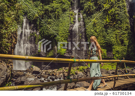 Woman in turquoise dress at the Sekumpul waterfalls in jungles on Bali island, Indonesia. Bali 61730134