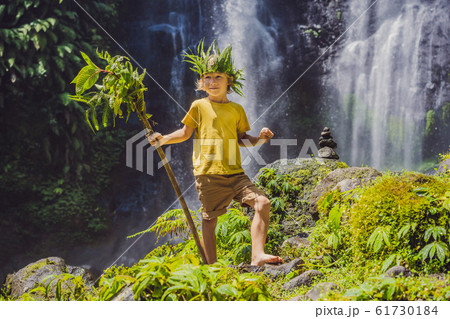 Cute boy depicts the king of the jungle against the backdrop of a waterfall. Childhood without Cute boy depicts the king of the jungle against the backdrop of a waterfall. Childhood without 61730184