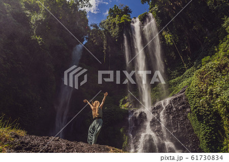 Woman in turquoise dress at the Sekumpul waterfalls in jungles on Bali island, Indonesia. Bali 61730834