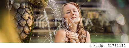 Young woman in hot springs banjar. Thermal water is released from the mouth of statues at a hot Young woman in hot springs banjar. Thermal water is released from the mouth of statues at a hot 61731152