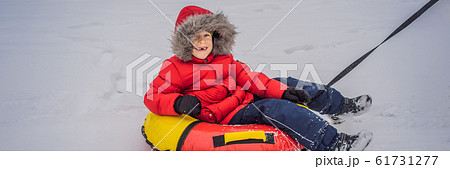 Child having fun on snow tube. Boy is riding a tubing. Winter fun for children BANNER, LONG FORMAT 61731277