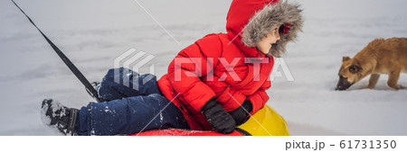 Child having fun on snow tube. Boy is riding a tubing. Winter fun for children BANNER, LONG FORMAT 61731350