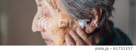 Senior woman listening to music on his smartphone, using modern wireless headphones BANNER, LONG Senior woman listening to music on his smartphone, using modern wireless headphones BANNER, LONG 61731357