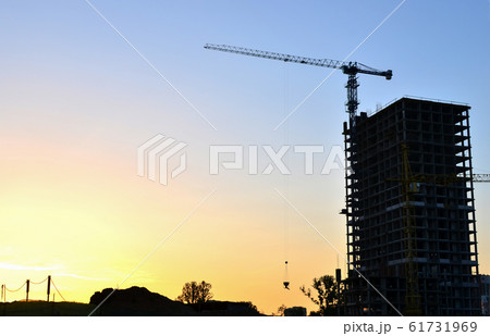 Tower crane constructing a new residential building at a construction site at sunset background. Tower crane constructing a new residential building at a construction site at sunset background. 61731969