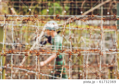 Barbed wire, a fence in prison and the silhouette of a prison guard on the background 61732369