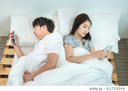 Young asian couple in bed using phone lying back to each other.relationship problem with technology. Young asian couple in bed using phone lying back to each other.relationship problem with technology. 61733044