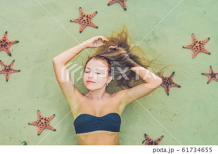 Young woman in the sea with red starfishes 61734655